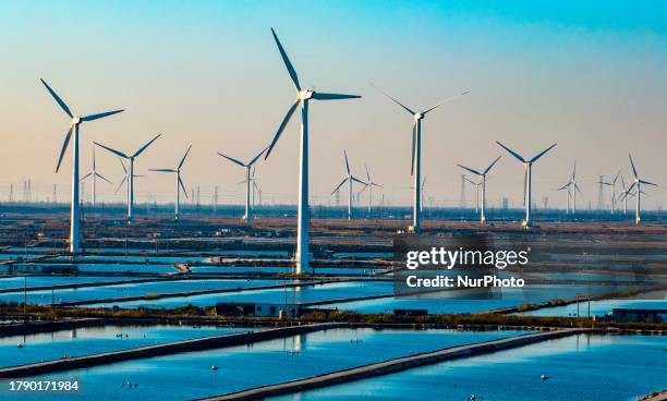 Wind turbine blades rotate in the tidal flat in Yancheng city, Jiangsu province, China, November 18, 2023.