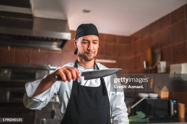 handsome chef ensures knife is ready for cooking - table knife stock pictures, royalty-free photos & images