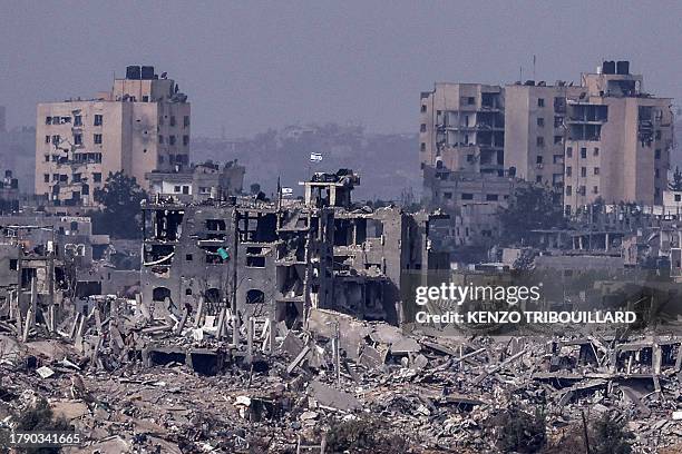This picture taken from southern Israel shows Israeli flags flying over destroyed buildings inside the Gaza Strip on November 19 amid ongoing battles...