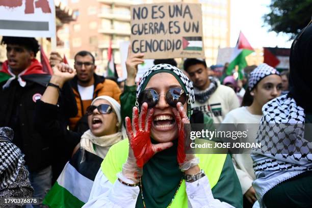 Protester with her hands painted red shouts slogans next to sign reading "It is not a war, it is a genocide" during a demonstration in support of the...