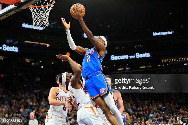 Shai Gilgeous-Alexander of the Oklahoma City Thunder attempts a layup over Josh Okogie of the Phoenix Suns during the first half at Footprint Center...