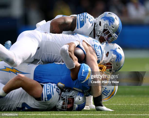 Austin Ekeler of the Los Angeles Chargers is tackled by Aidan Hutchinson and Derrick Barnes of the Detroit Lions on top of Jack Campbell during the...