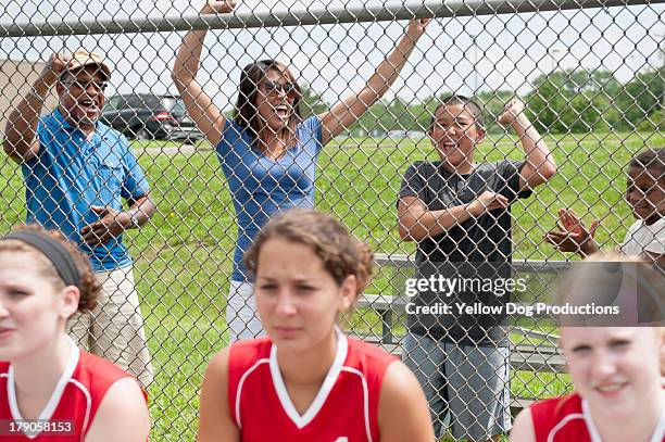families cheering teen softball players - softball sport stock-fotos und bilder