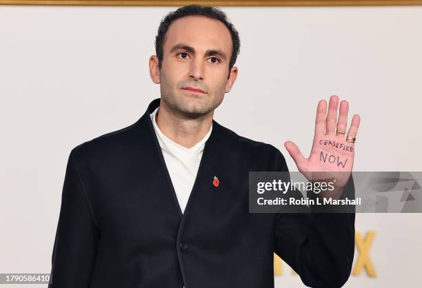Khalid Abdalla, with "ceasefire now" written on the palm of his hand, attends the Los Angeles Premiere of Netflix's "The Crown" Season 6 Part 1 at...