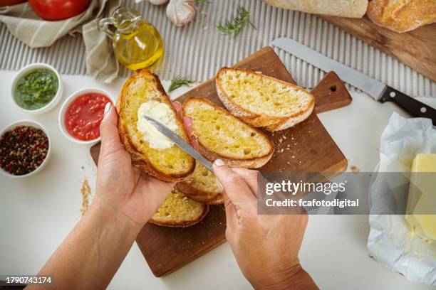 woman hands spreading butter on bread slices - garlic bread stock pictures, royalty-free photos & images