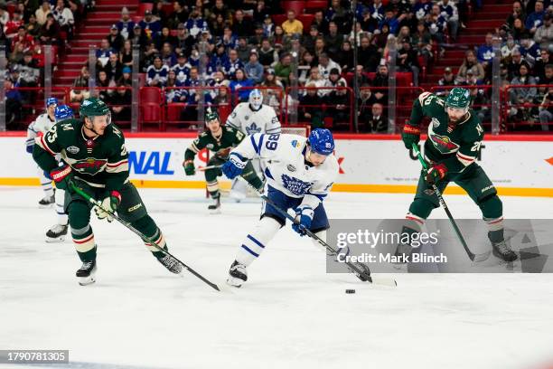 Nicholas Robertson of the Toronto Maple Leafs plays the puck against Jonas Brodin and Pat Maroon of the Minnesota Wild during the second period...