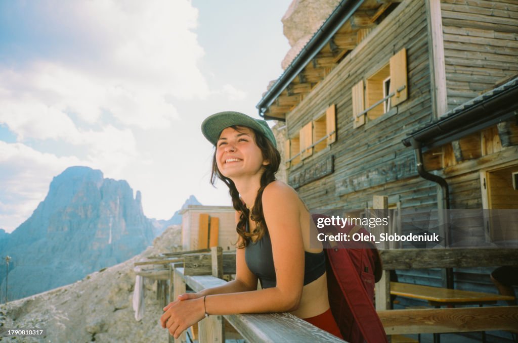 Femme joyeuse debout sur le porche d’un refuge de montagne dans les Dolomites