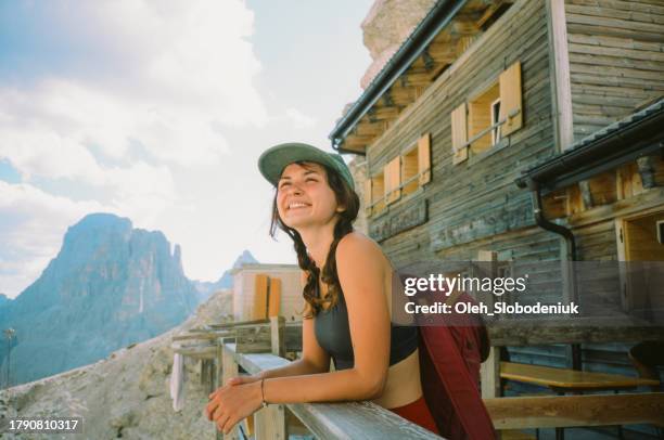 cheerful woman standing on the porch of mountain hut in dolomites - hut stockfoto's en -beelden