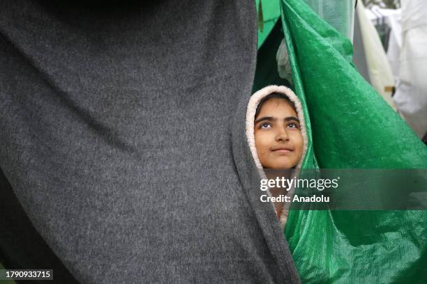 Child is seen as Palestinians, who are migrate to the around the Al-Aqsa Martyrs Hospital for shelter, struggle with rain and cold weather as Israeli...