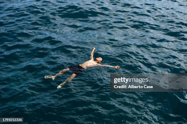 a man floating in the sea - flotar sobre agua fotografías e imágenes de stock