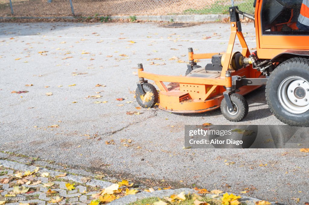 Someone cleans the autumn leaves on the street with a machine.