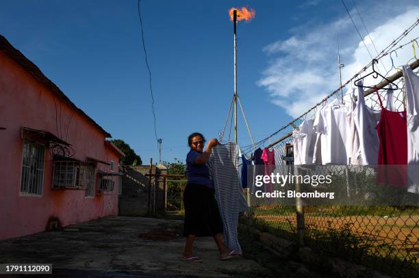 Resident hangs clothes to dry outside a home near a Petroleos de Venezuela SA oil flare in Cabimas, Zulia state, Venezuela, on Friday, Nov. 17, 2023....