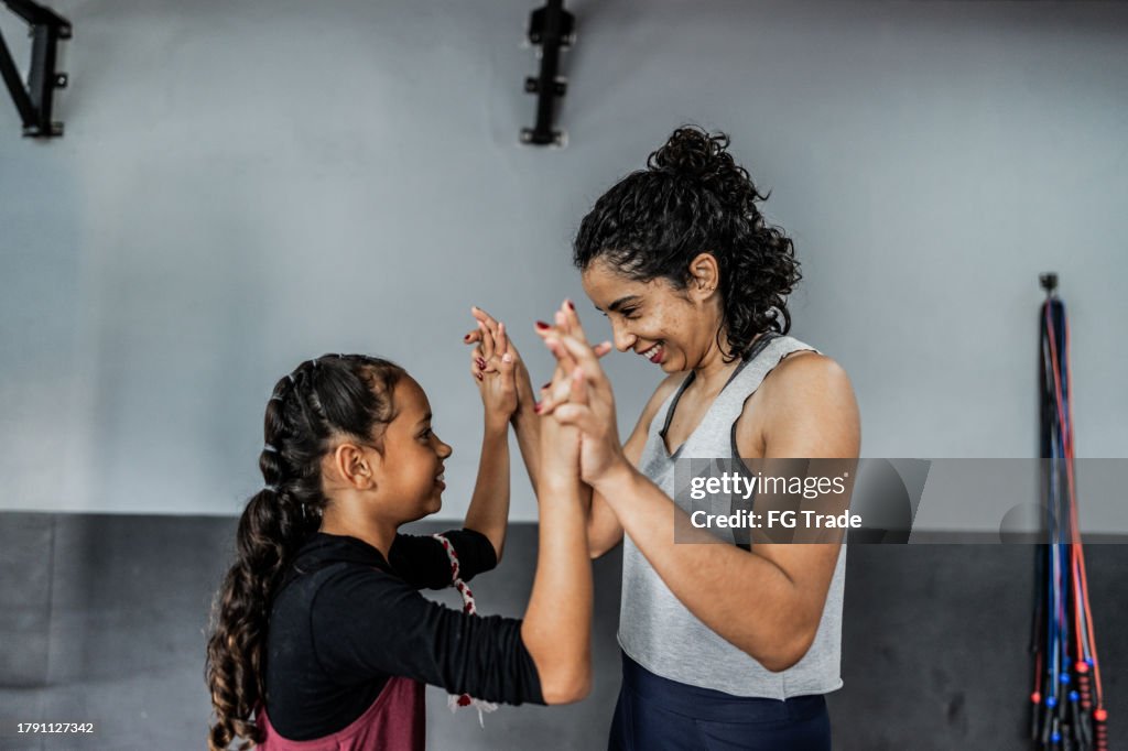 Boxlehrer begrüßt ein Kindermädchen im Fitnessstudio