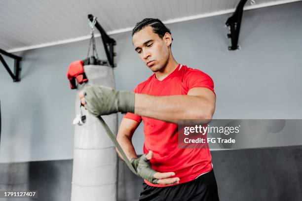 young man putting elastic bandage on hands at boxe gym - ace bandage stock pictures, royalty-free photos & images