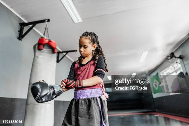 niña que pone guantes de boxeo en el gimnasio - muay thai fotografías e imágenes de stock