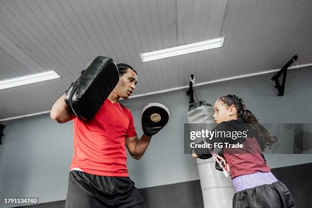 child girl practicing boxing or muay thai with instructor at gym - muaythai boxing stock pictures, royalty-free photos & images