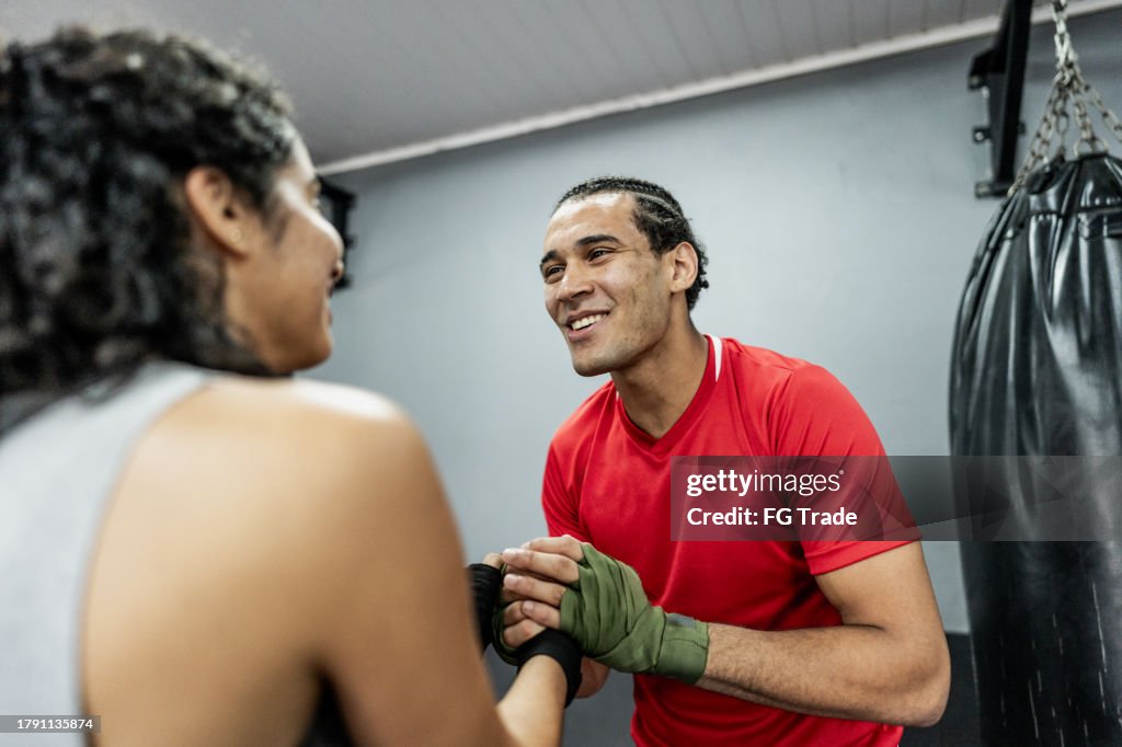 Boxe instructor and mid adult woman greeting at gym