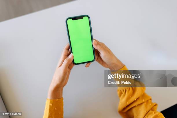 unrecognisable woman using phone with a green screen on it - green screen stock pictures, royalty-free photos & images