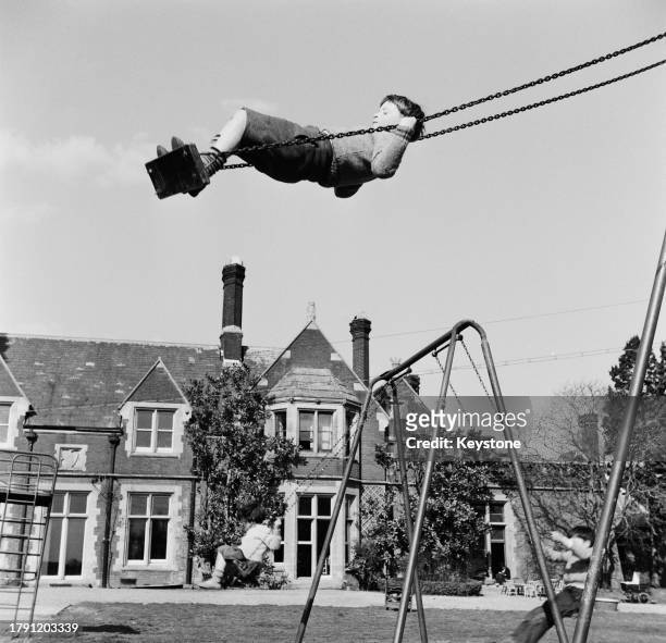 Children swinging in the grounds of Bulstrode Park manor house which is home to members of the Society of Brothers community , Buckinghamshire, April...