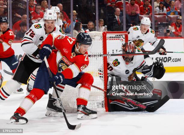 Alex Vlasic of the Chicago Blackhawks defends against Eetu Luostarinen of the Florida Panthers as he attempts a shot against goaltender Arvid...