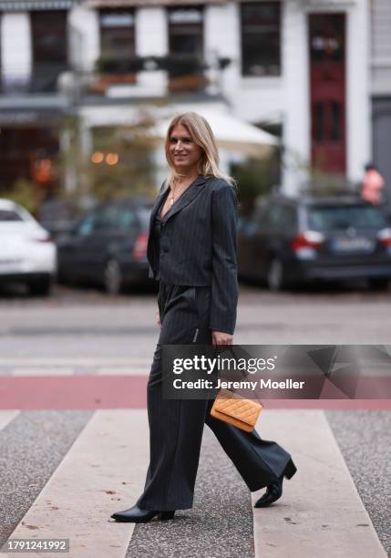 Britta Becker seen wearing gold necklace, TWELVE by Britta Becker dark grey striped suit vest, matching TWELVE by Britta Becker dark grey striped...