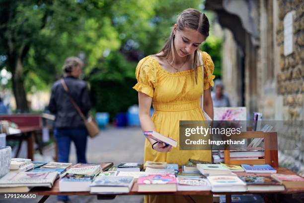 adolescente hojeando libros en un mercadillo benéfico. - stand fotografías e imágenes de stock