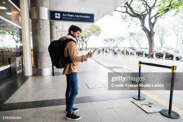 traveler mid adult man using mobile phone outside the airport - uber in buenos aires argentina stock pictures, royalty-free photos & images