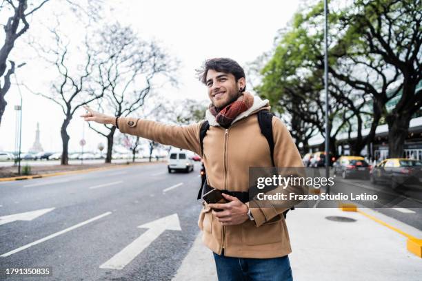 traveler mid adult man using mobile and waiting taxi outdoors - uber in buenos aires argentina stock pictures, royalty-free photos & images