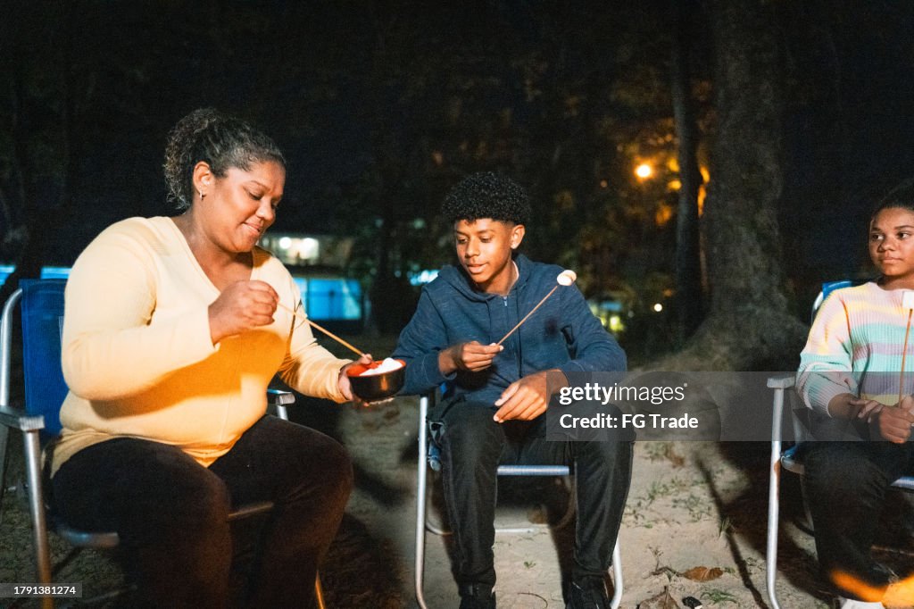 Family eating roasted marshmallows on a campsite in the forest