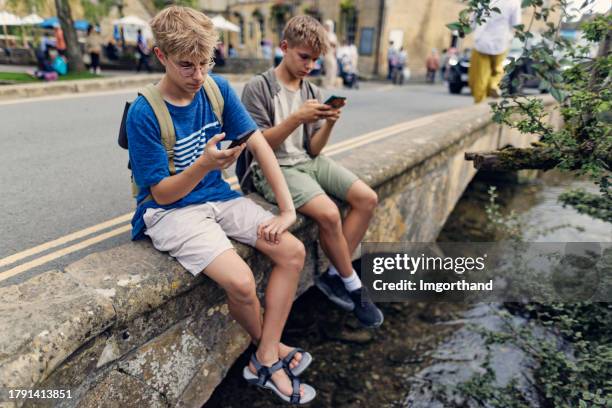 teenagers "sightseeing" the beautiful village of bourton-on-the-water - season 14 stockfoto's en -beelden