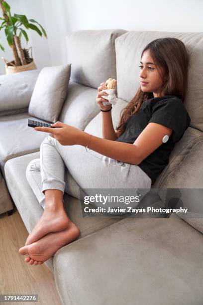 teenage girl eating a sandwich while watching tv at home - changing channels stock pictures, royalty-free photos & images