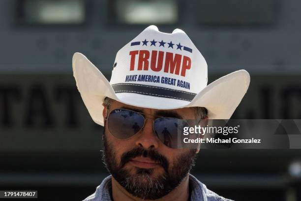 Man wearing a Donald Trump hat waits to hear the former president speak at the South Texas International airport on November 19, 2023 in Edinburg,...