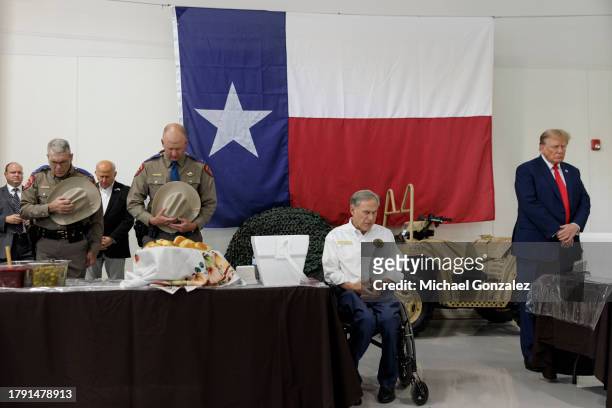 Former President Donald Trump and Texas Governor Greg Abbott bow their heads during a prayer at the South Texas International airport on November 19,...