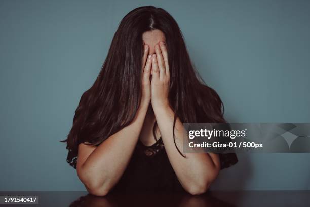 close-up of young woman with long brown hair over face against gray background - covering gray hair stock pictures, royalty-free photos & images