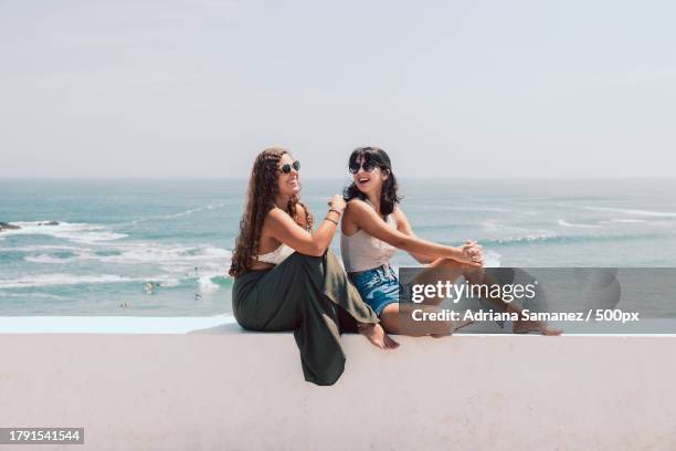 portrait of two friends spending quality time together at beach during day against sea,san bartolo,peru - summer images stock pictures, royalty-free photos & images