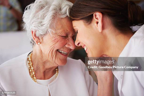 高齢者の女性顔に触れている若い女性の看護師 - nursing home smiling ストックフォトと画像