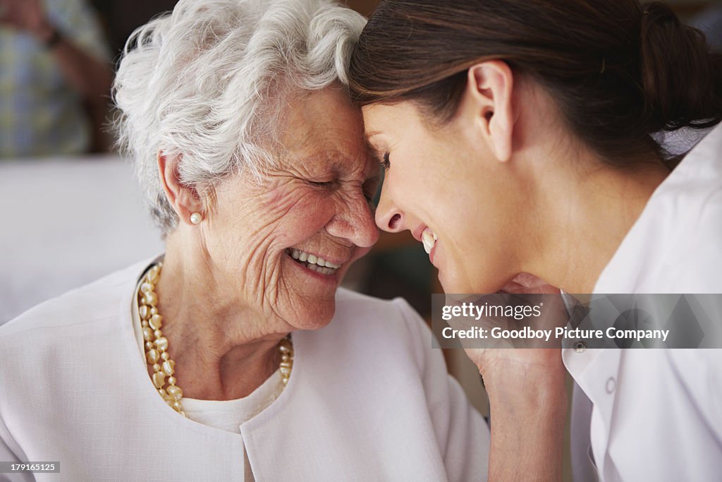 Elderly woman touching face of young female nurse