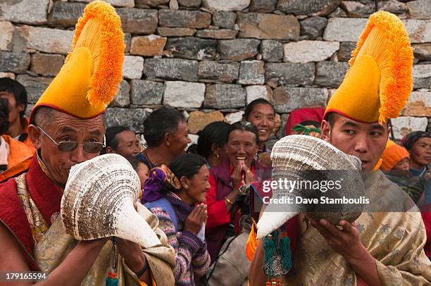 Yellow hat monks blowing conch shells at the Mani Rimdu Festival at Tengboche Monastery in the Everest Region of Nepal