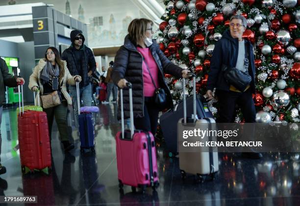 Travelers walk past a Christmas tree at JFK Airport in New York on November 19, 2023.