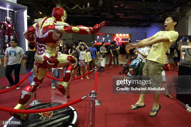 Man pose for a photo with a life size replica of Iron Man during the Singapore Toy, Game & Comic Convention at the Sands Expo & Convention Centre at...