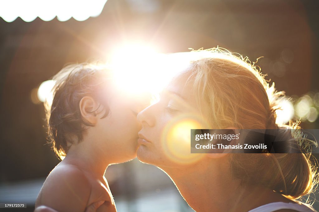 Small boy kissing his mother