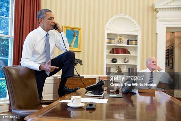 In this handout provided by the White House, U.S. President Barack Obama talks on the phone with Speaker of the House Boehner as Vice President Joe...
