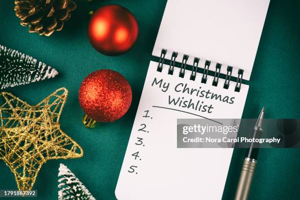 my christmas wish list text on note pad with christmas decorations - christmas list stock-fotos und bilder