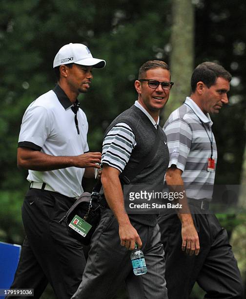 Tiger Woods, swing coach Sean Foley and agent Mark Steinberg walk to the ninth hole during a practice round at the Deutsche Bank Championship at TPC...
