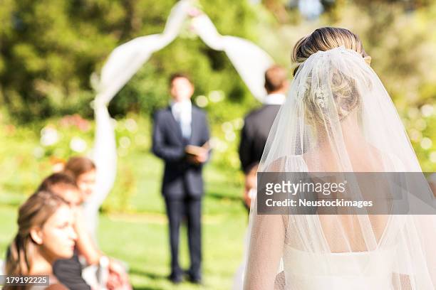 bride wearing veil walking down the aisle during garden wedding - wedding ceremony bildbanksfoton och bilder