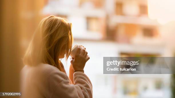morning tranquility: woman sips coffee on balcony, ready for the day - balcony stock pictures, royalty-free photos & images