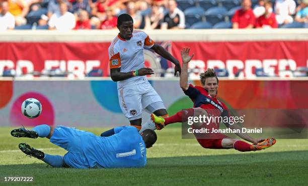 Tally Hall of the Houston Dynamo makes a save against Chris Rolfe of the Chicago Fire as Kofi Sarkodie defends during an MLS match at Toyota Park on...