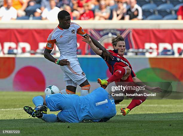 Tally Hall of the Houston Dynamo makes a save against Chris Rolfe of the Chicago Fire as Kofi Sarkodie defends during an MLS match at Toyota Park on...