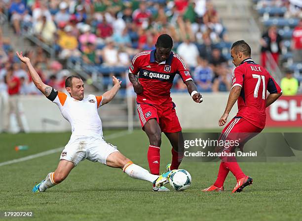 Brad Davis of the Houston Dynamo kicks the ball between Jalil Anibaba and Alex of the Chicago Fire during an MLS match at Toyota Park on September 1,...