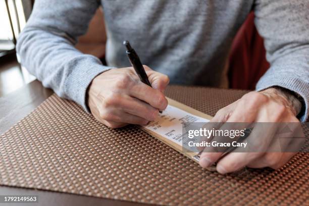 man signs credit card receipt at restaurant - gratuity stock pictures, royalty-free photos & images